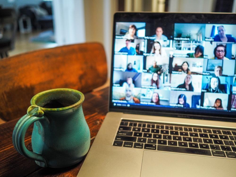 A mug and laptop screen showing a Zoom call