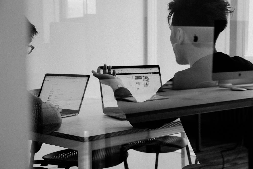 Two people looking at laptop screens.